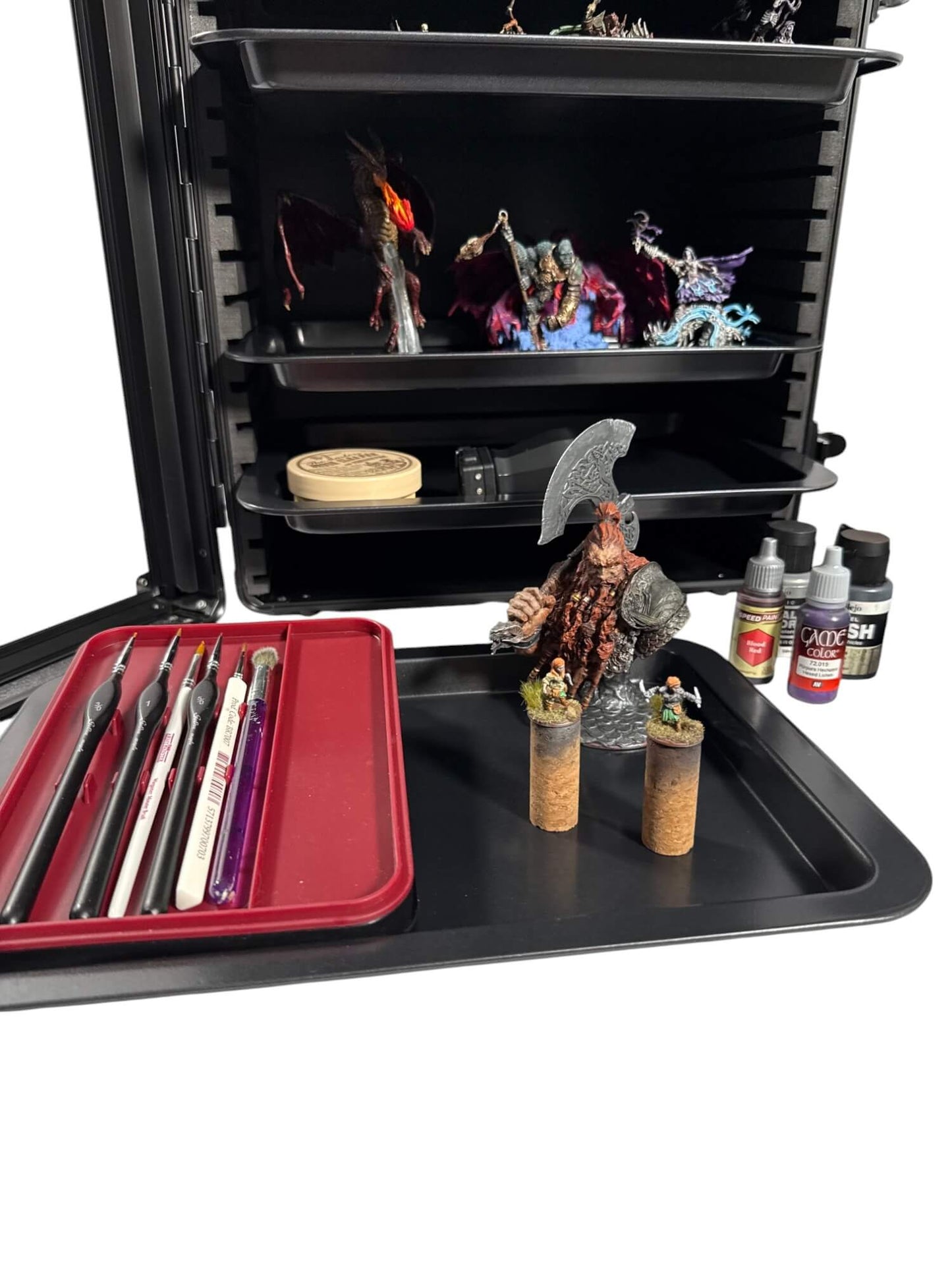 Modeling tools and supplies on a black tray with figurines and paint bottles.