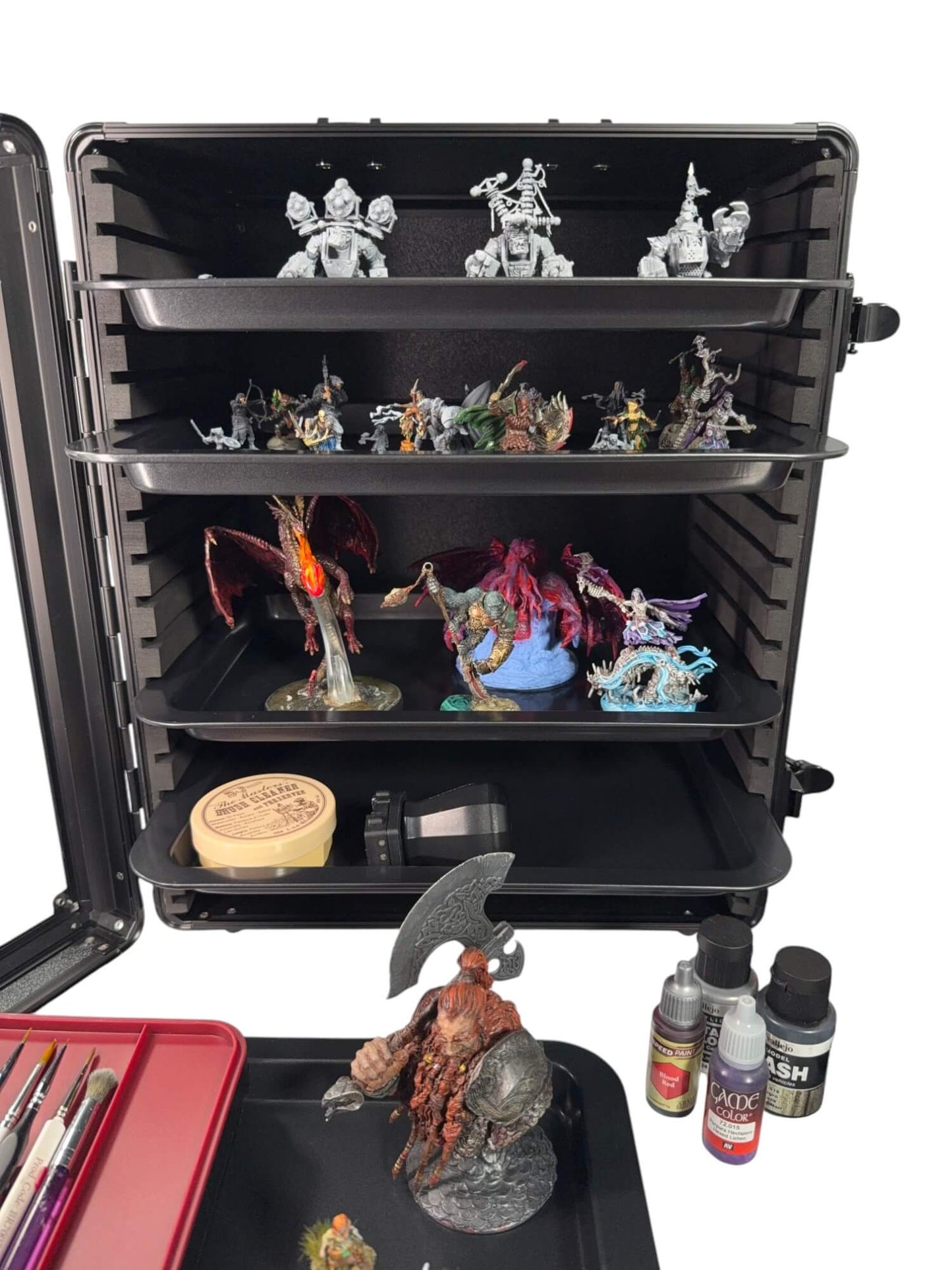 Black storage case with shelves displaying miniature figurines and painting supplies on a white background