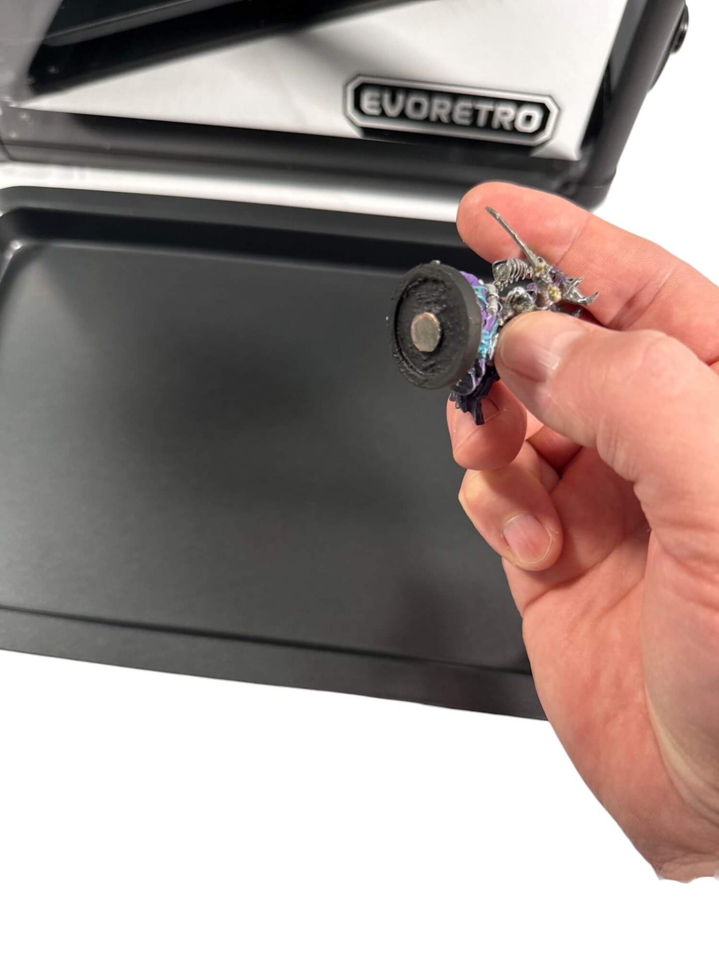 Hand holding a small mechanical component in front of an Evoretro case.