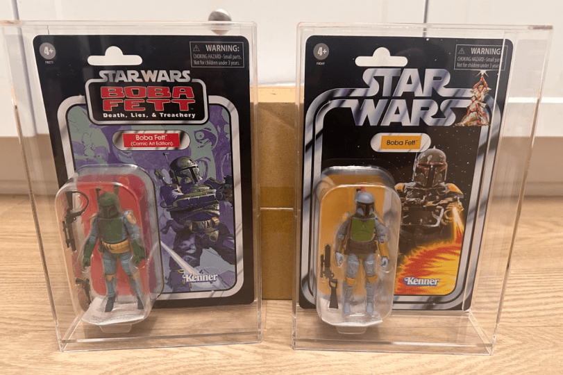 Two Star Wars Boba Fett action figure packages on a wooden surface.