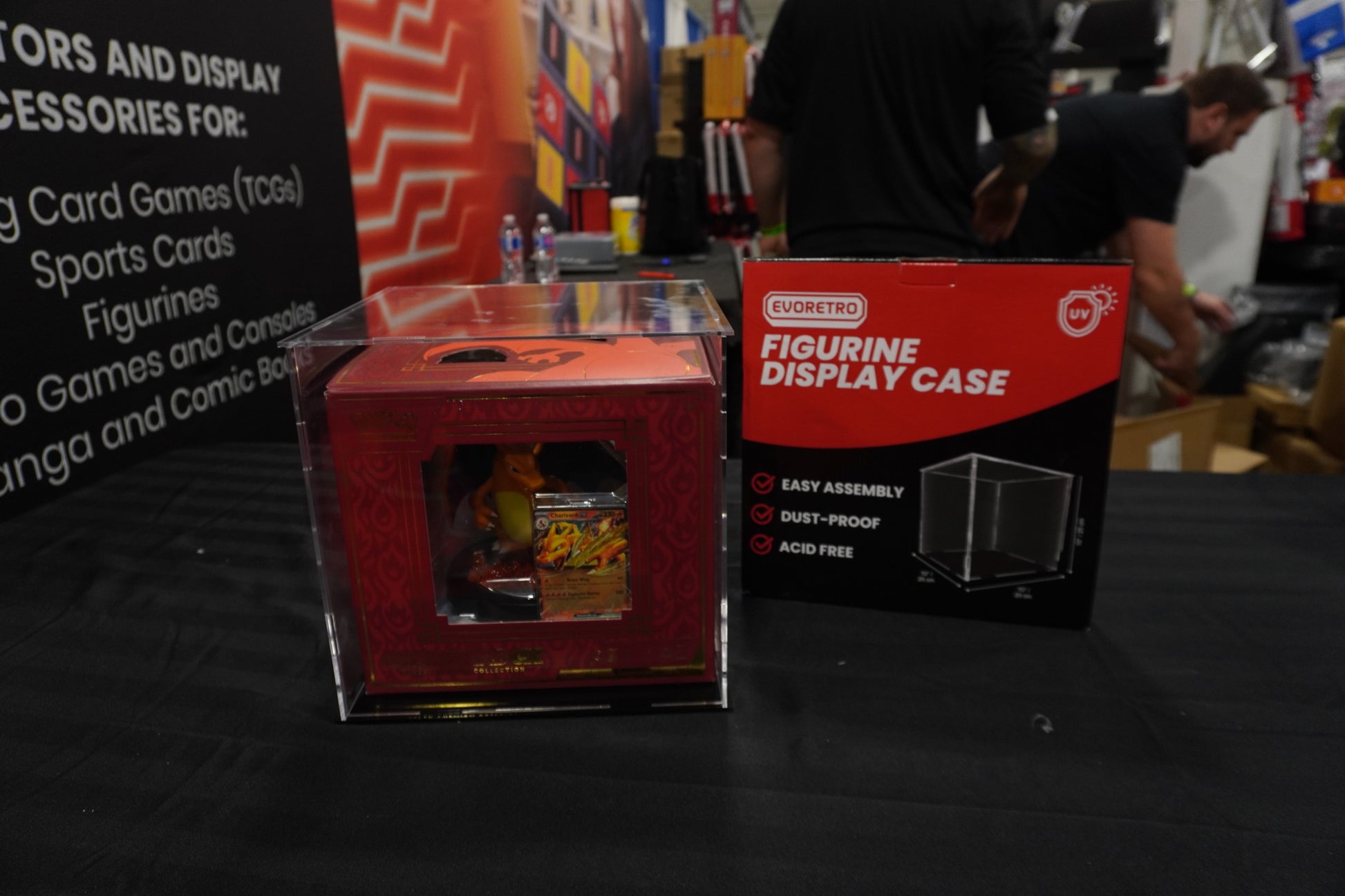Red figurine display case with a small figurine inside, on a black surface with a blurred background.