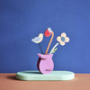 Colorful paper craft of a vase with flowers and a bird on a blue background